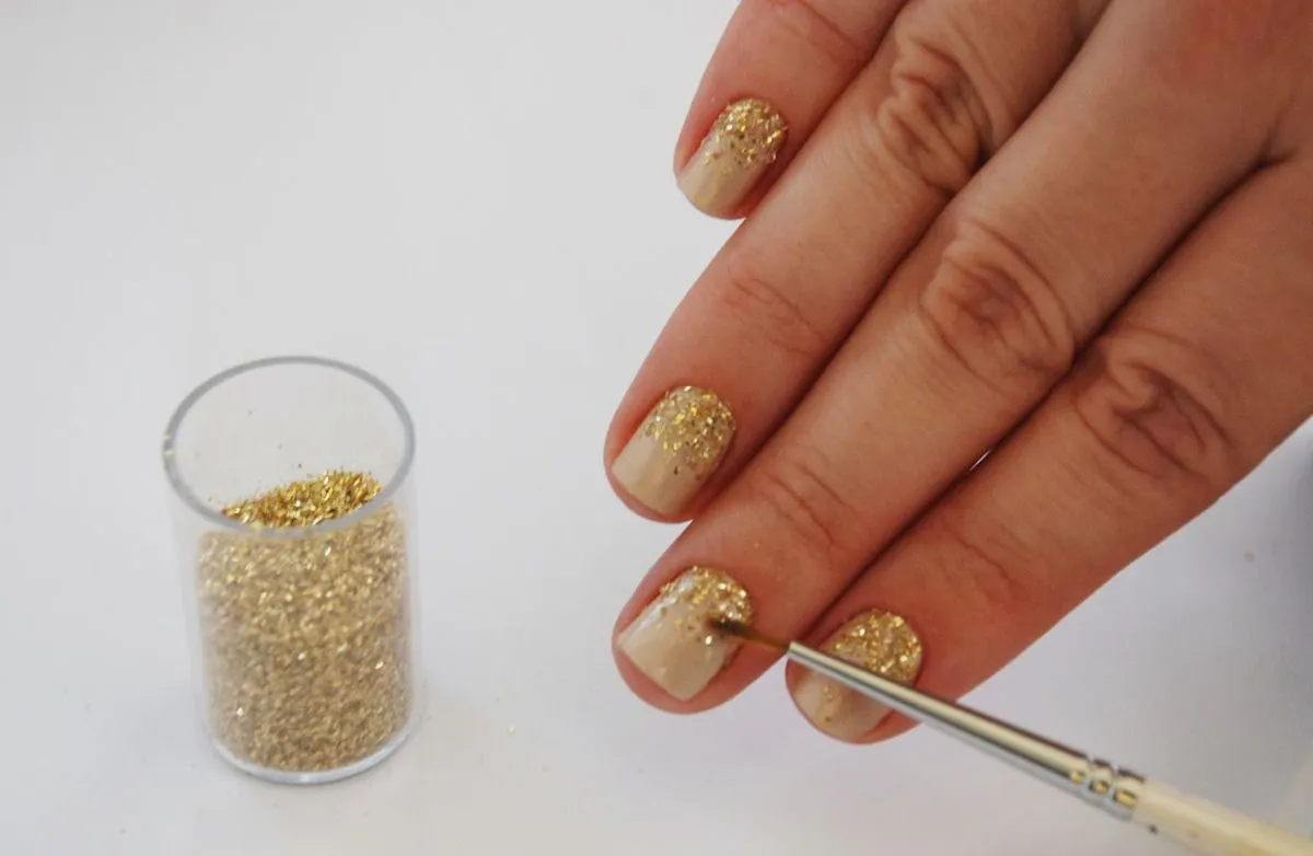 Aplicação de glitter dourado nas unhas