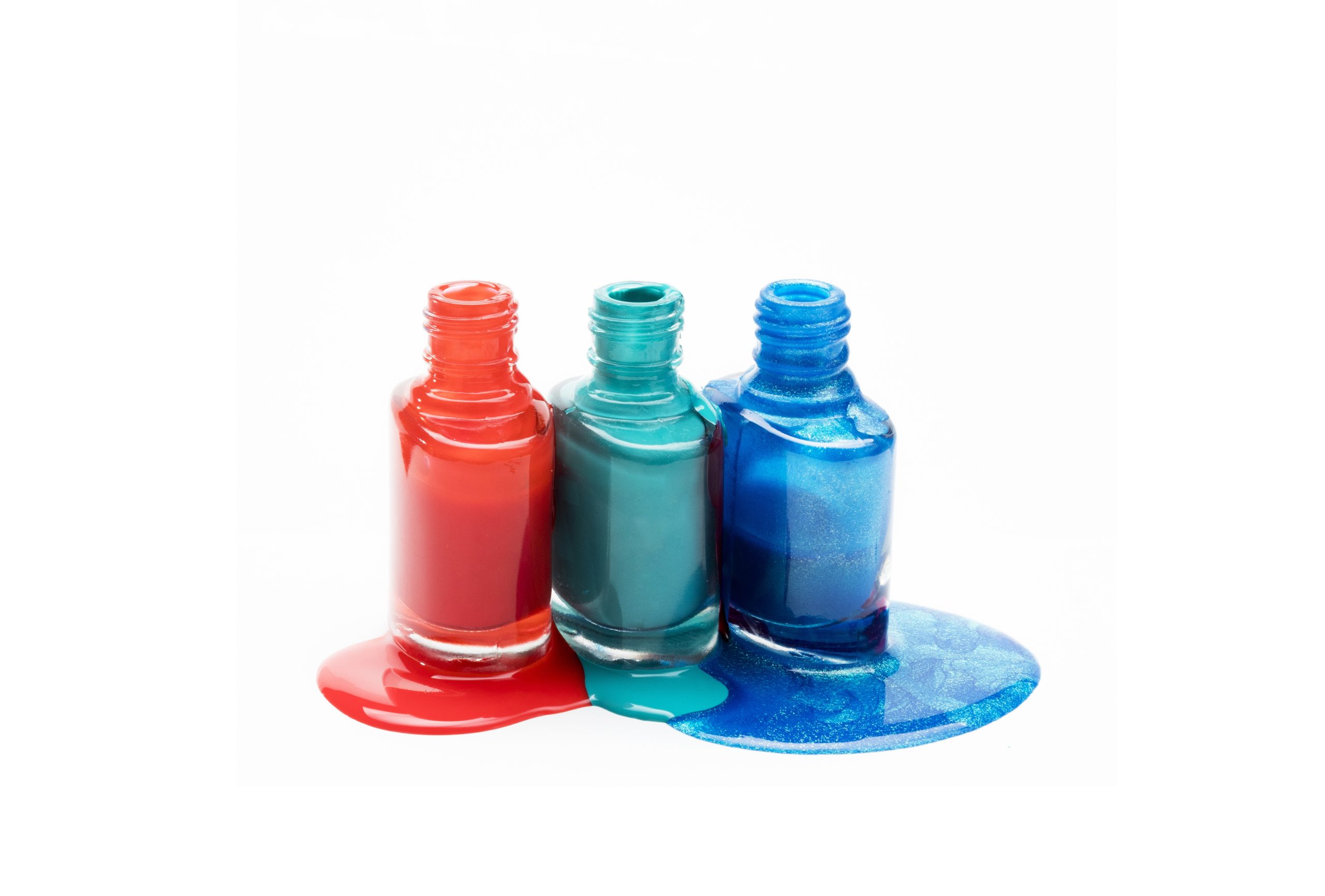 vidros de esmalte nas cores laranja, verde e azull abertos com liquido derramado em seu entorno