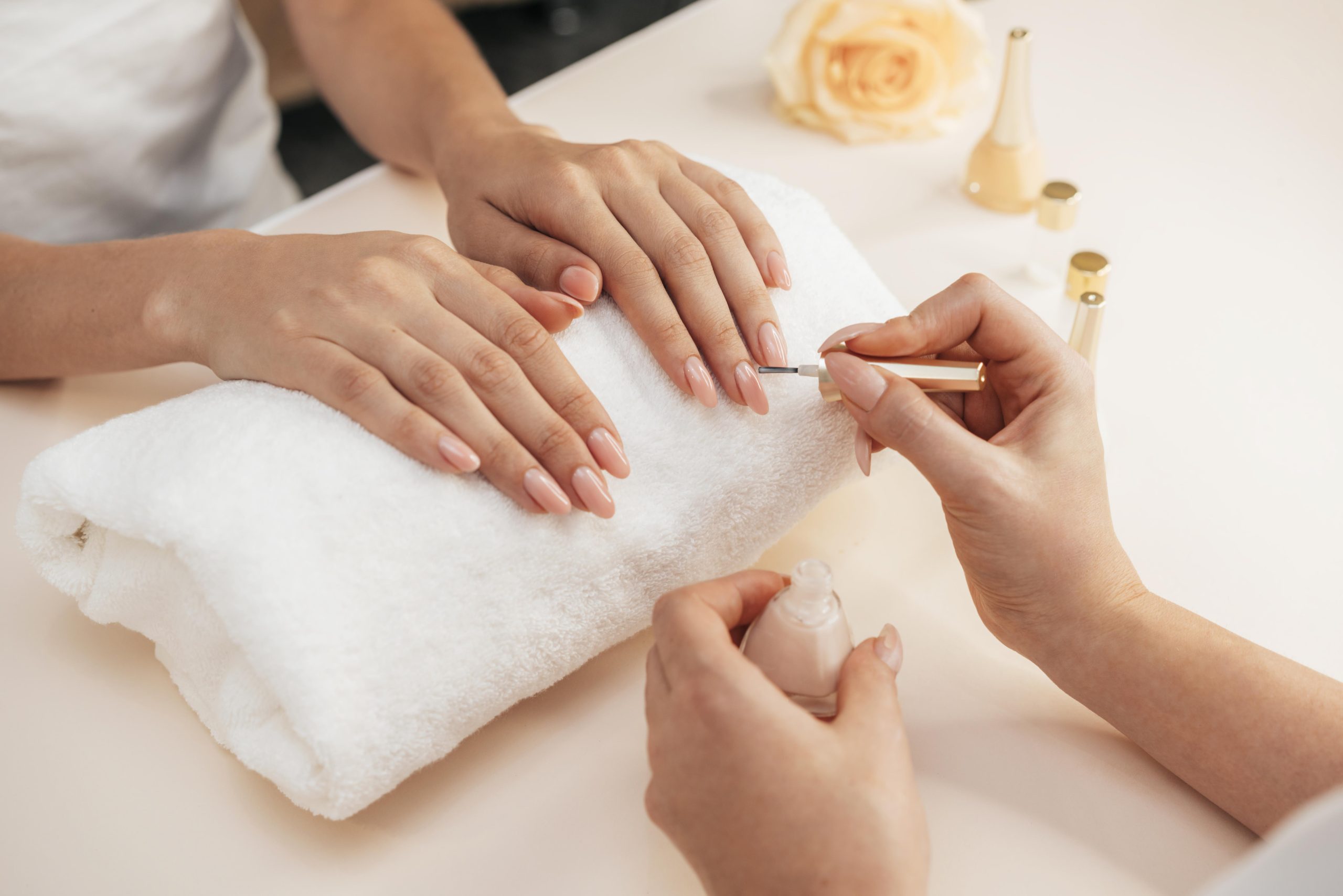Profissional manicure faz esmaltação de unhas das mãos de cliente
