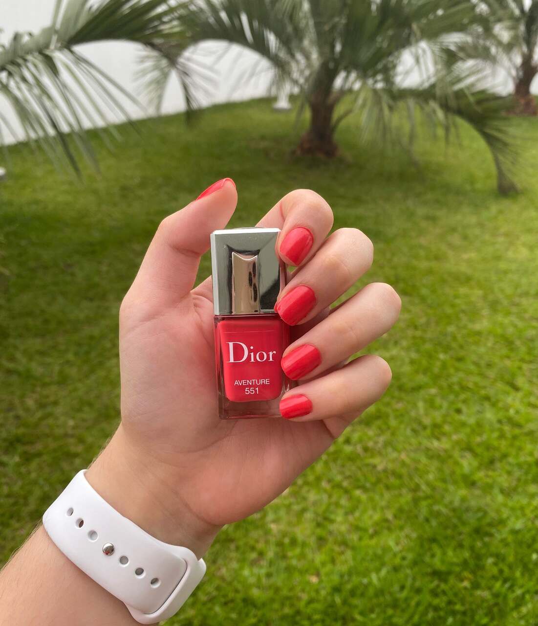 Mão feminina com esmatel 551 Dior Aventure vermelho aberto 