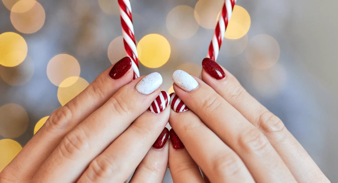 Unhas curtas com decorações natalinas de glitter vermelho e listras brancas 