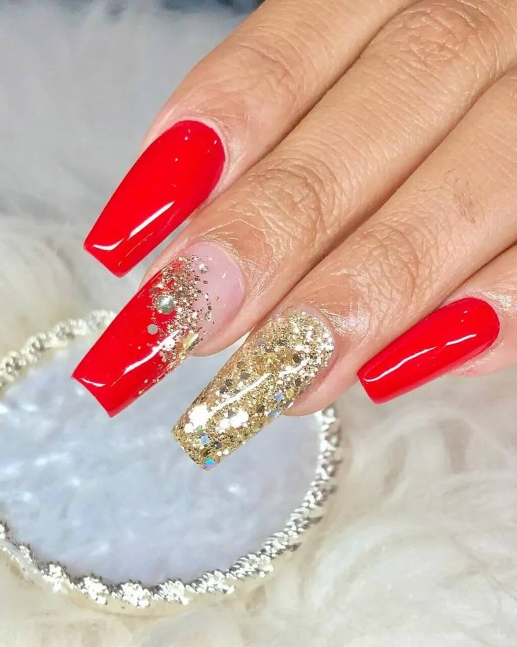 Unhas vermelhas e douradas com glitter no dedo anelar 